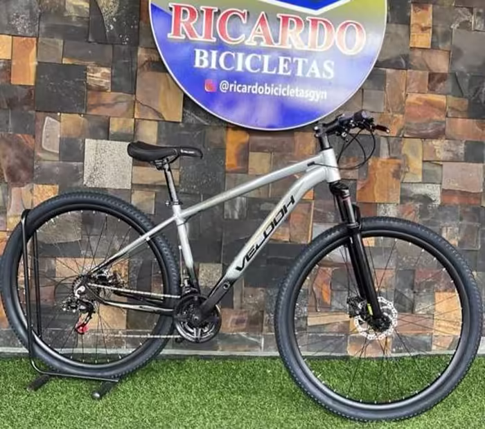 Bicicleta Velooh aro 29 prata em frente ao painel da loja