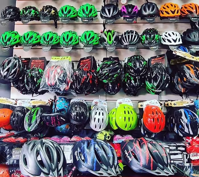 Parede da loja com dezenas de capacetes de ciclismo expostos
