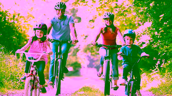 Família com dois filhos pedalando junta em uma trilha arborizada